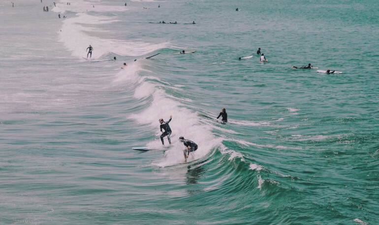Surfers riding a wave and sitting on surfboards in the ocean